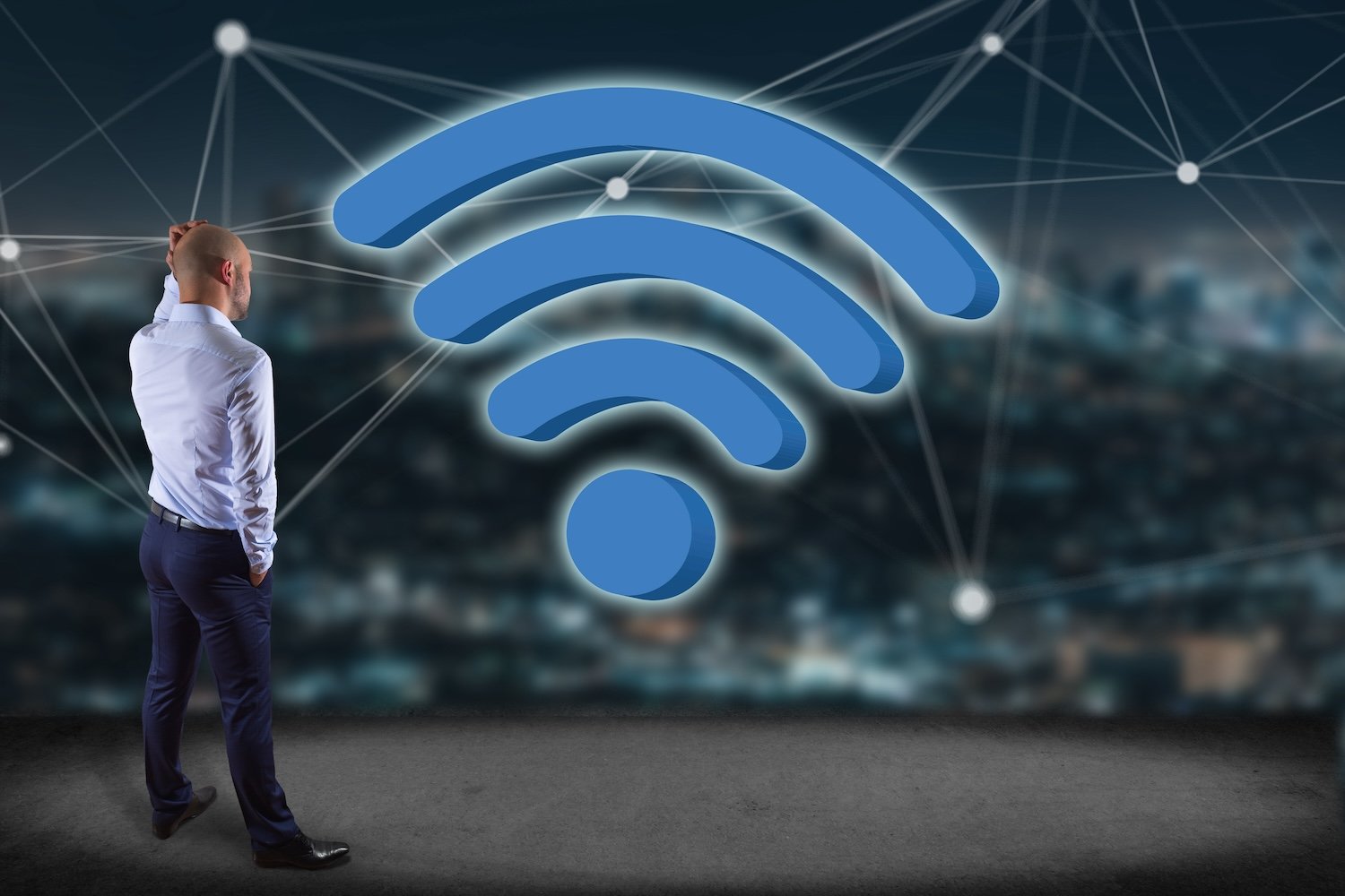 Man standing in front of a huge Wi-Fi icon, with a nighttime cityscape in the background 